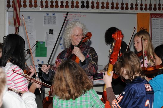 Martha Mooke demonstrating string techniques for students at a clinic.