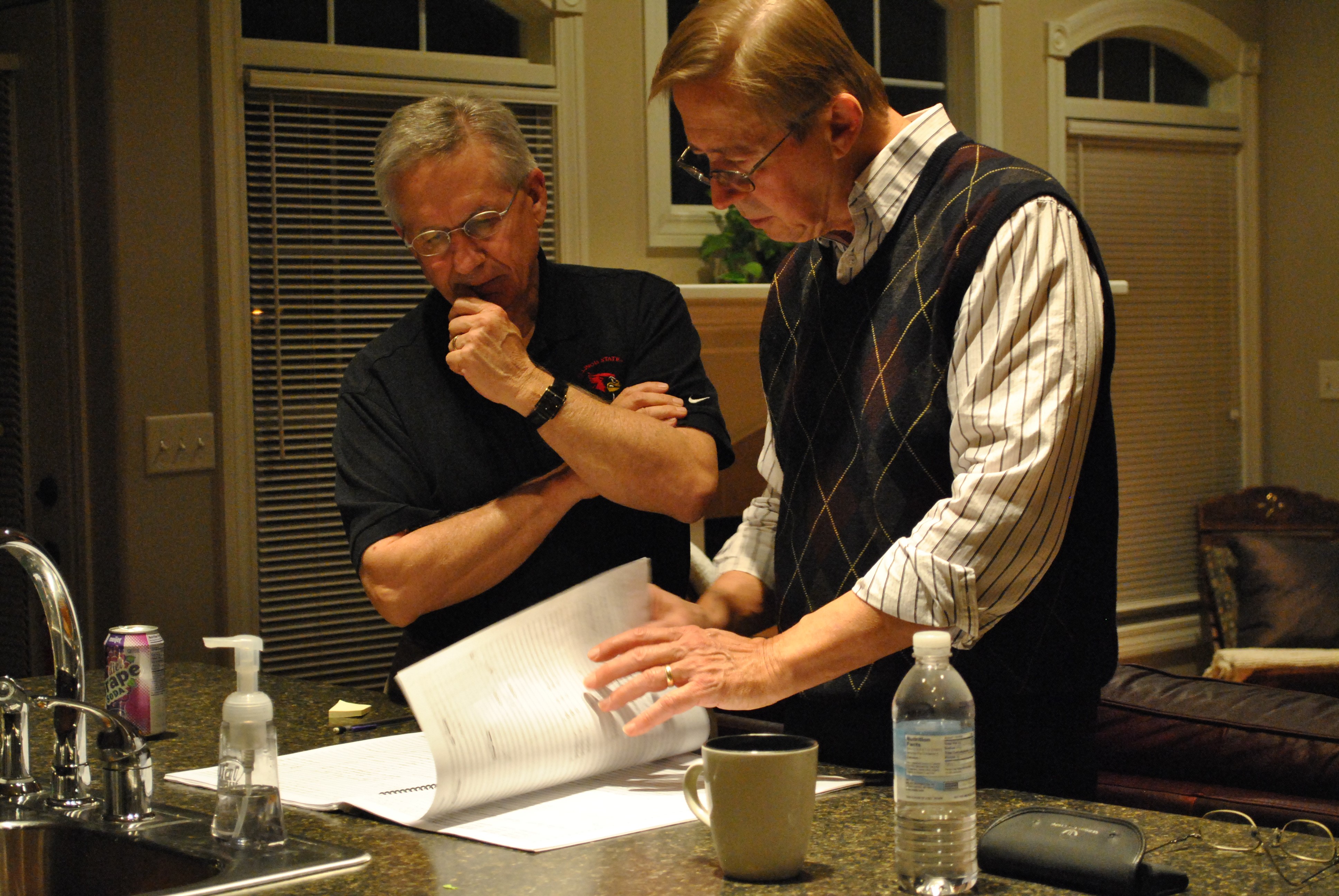 Stephen K. Steele and David Maslanka looking through one of his scores near a kitchen sink.