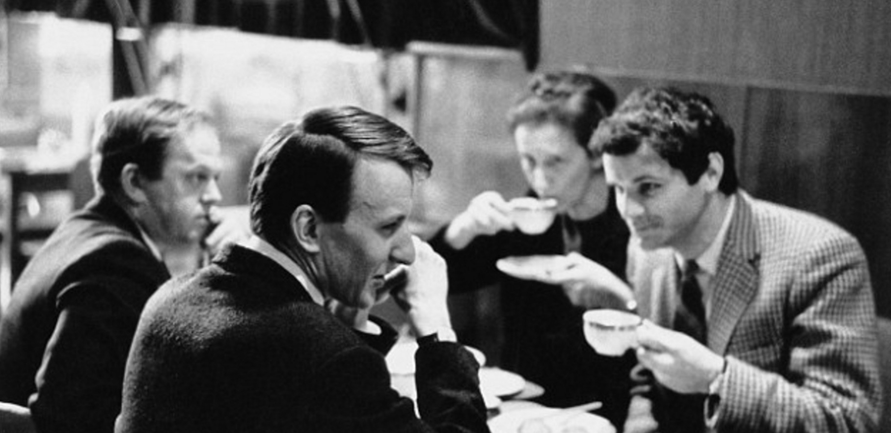 A 1965 photo of Malcolm Williamson, Richard Rodney Bennett, Thea Musgrave, and Peter Maxwell Davies at a cafe; Musgrave and Maxwell Davies are drinking from teacups.