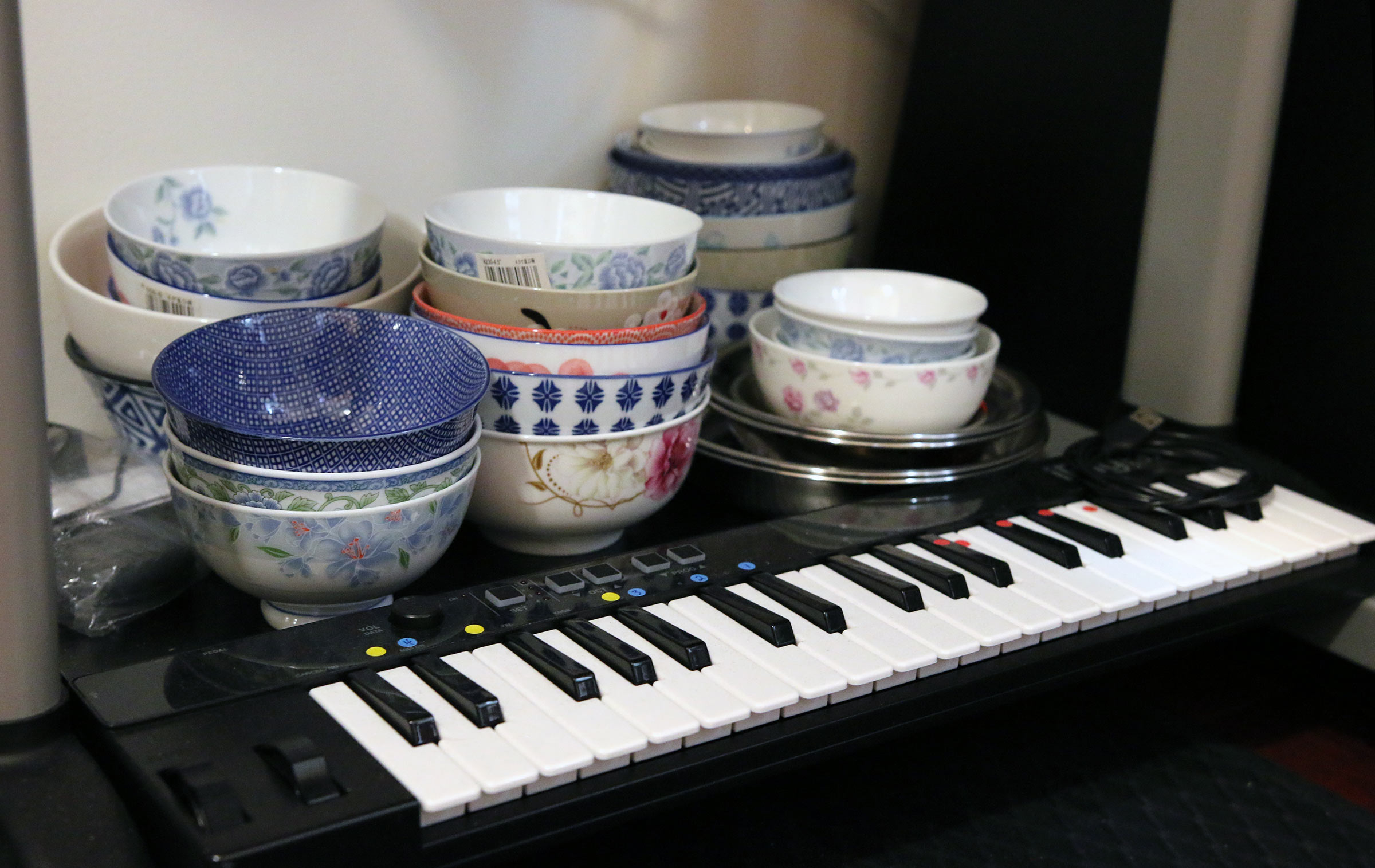 A group of ceramic bowls in back of a sampling keyboard.