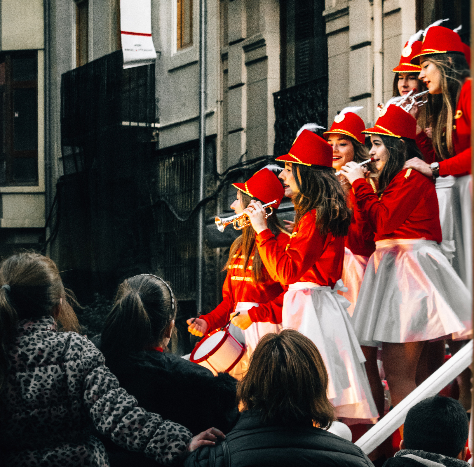 An audience watches a female marching band. Photo by Jānis Skribāns via Unsplash (https://unsplash.com/@janisskribans) 