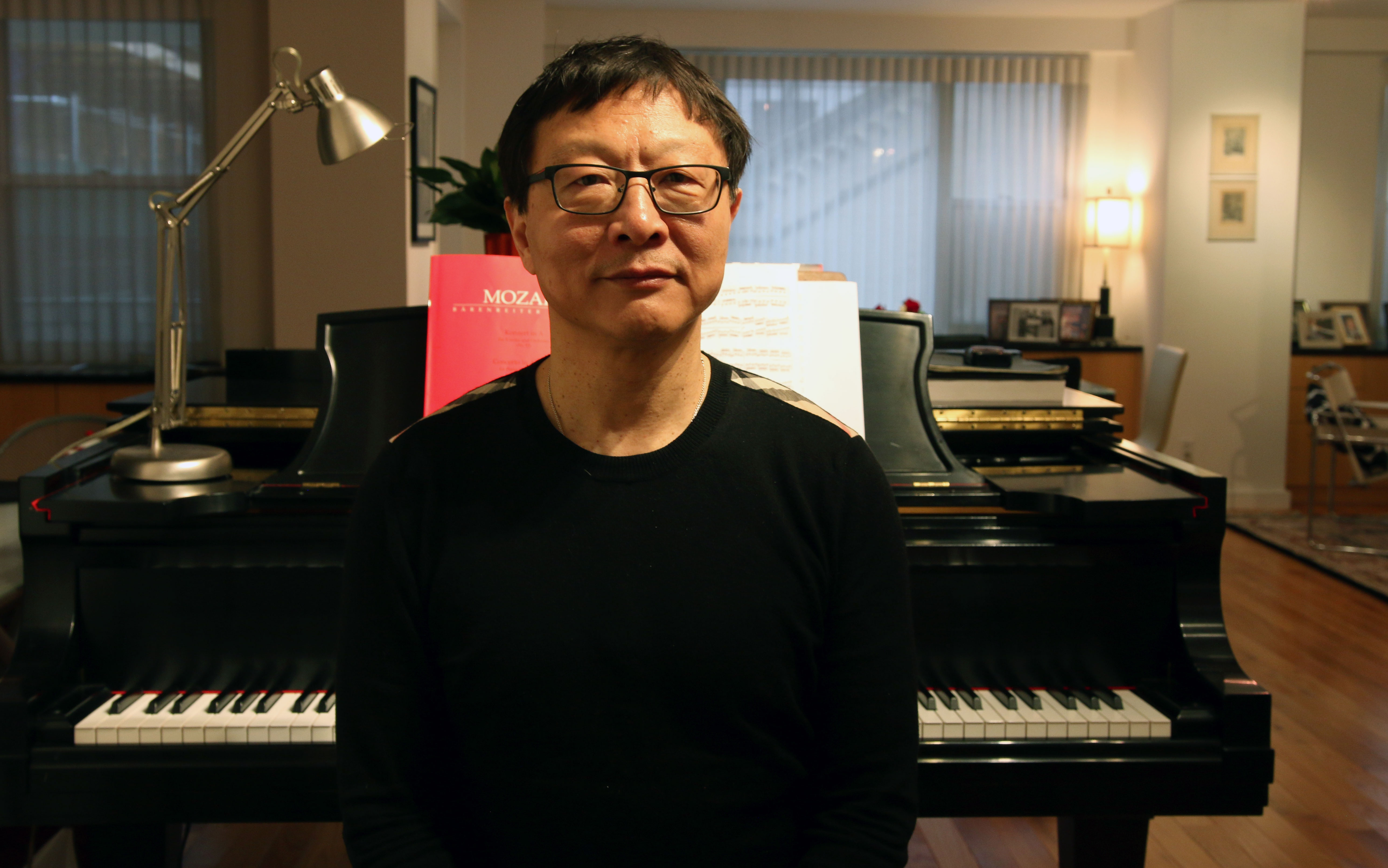 Bright Sheng sitting in front of his grand piano