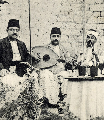 An historic photo of 3 Aleppo musicians performing (from left to right) on some sort of not completely identfiable frame drum, an oud, and a ney