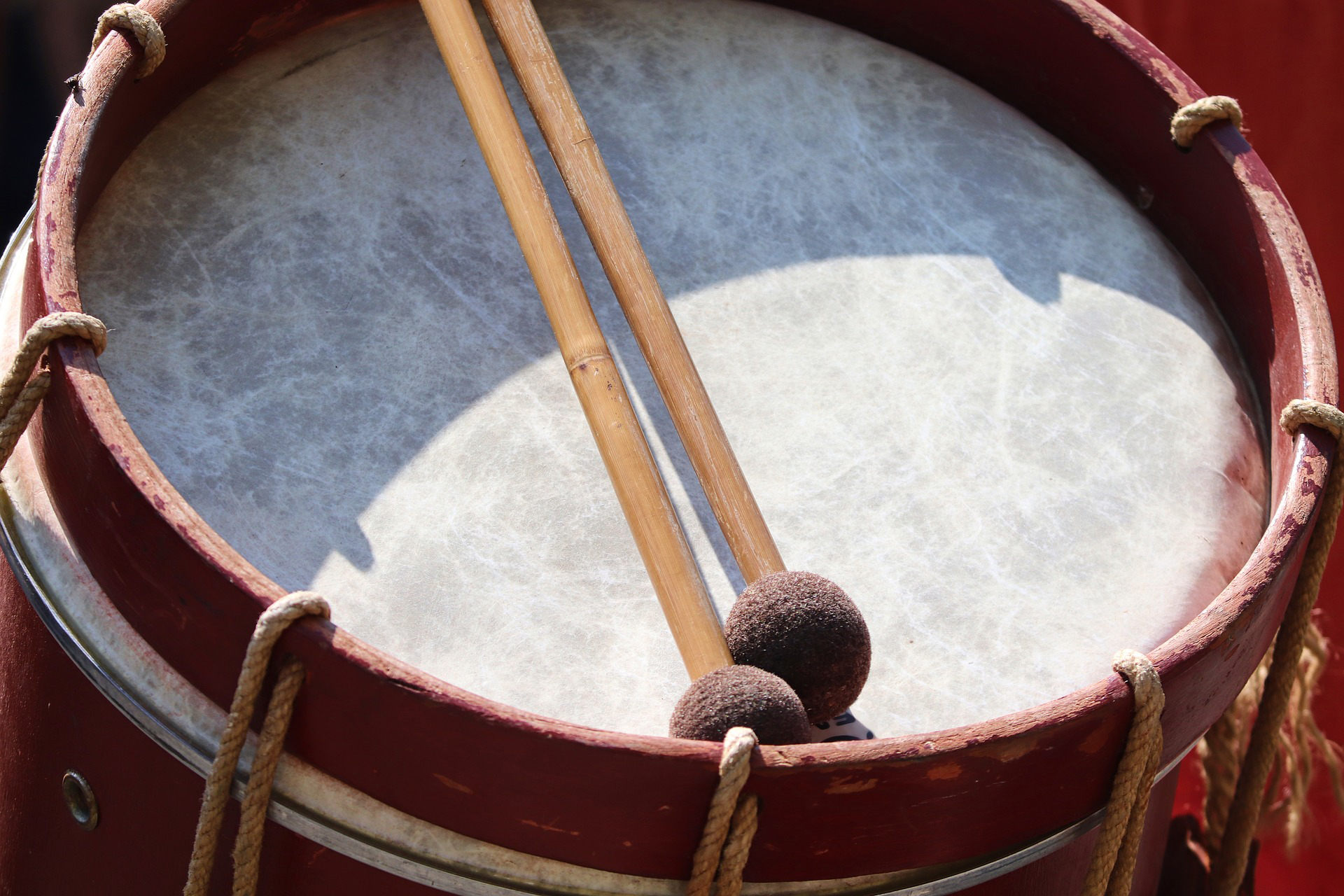 A close up of a drum head of a marching band tenor drum with two mallets resting on ots surface.