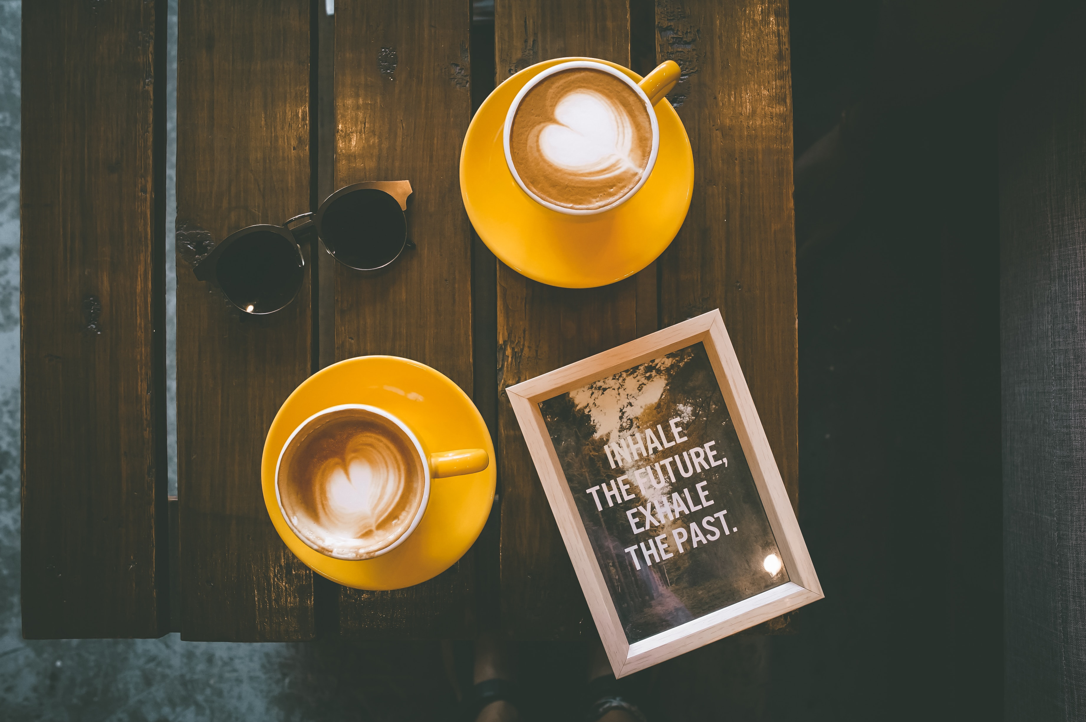 A photo from Cebu City, Philippines, showing two mugs containing cappuccinos on a table alongside a picture frame containing a quote with these words all in capital letters: 