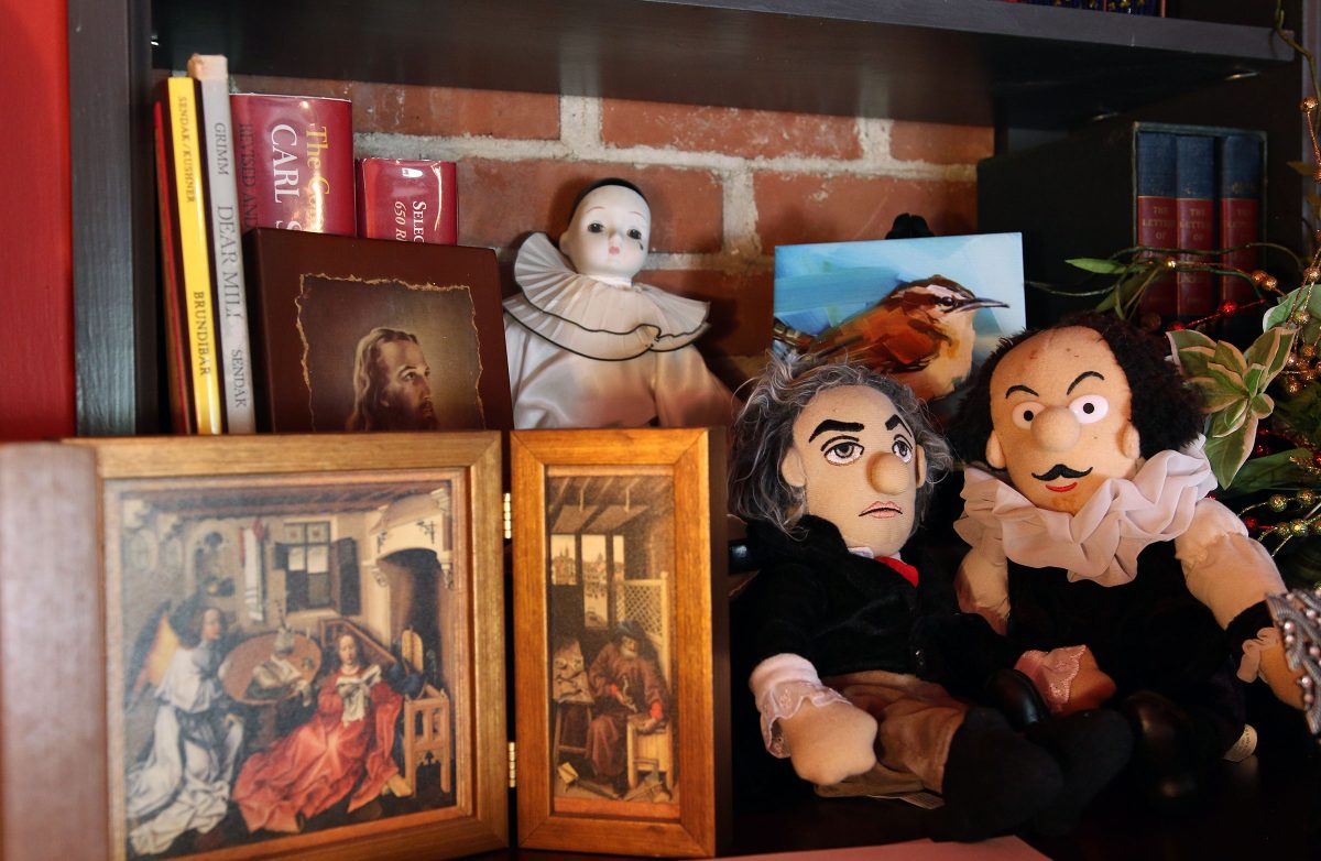 One of Juliana Hall's shelves filled with puppets of famous composers, poetry books, paintings and religious items.