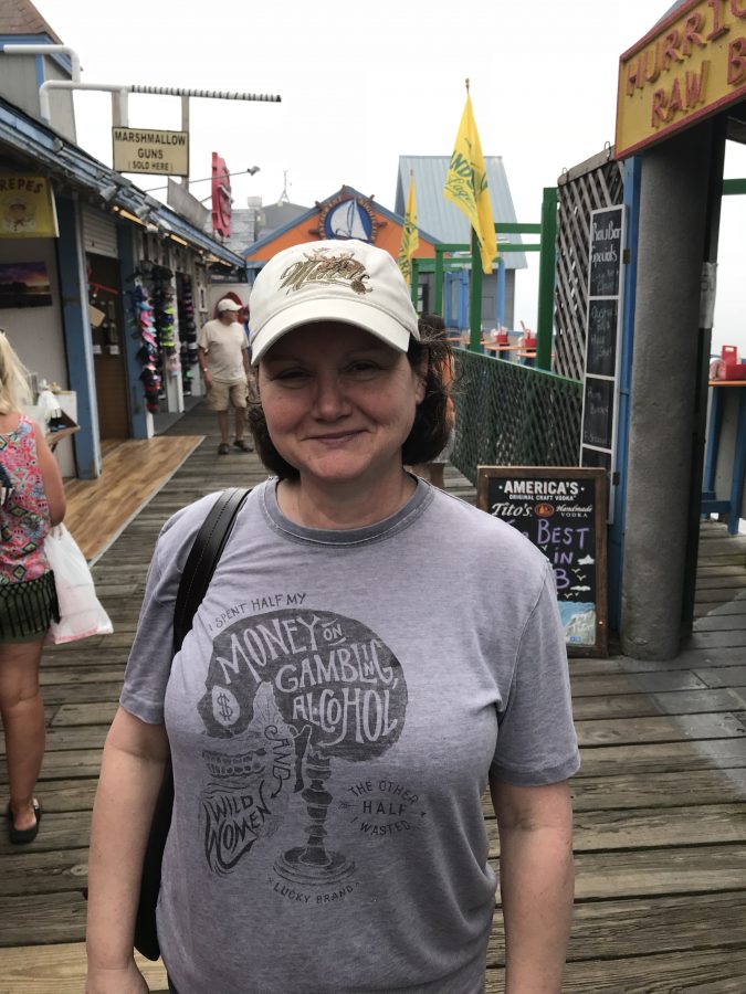 Julie Giroux walking on a boardwalk wearing a cap and a T-shirt which reads: 